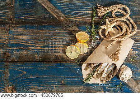 Sun-dried Smelt In A Paper Package. Salted Fish With Marine Decor. Lemon, Fresh Rosemary, Sea Rope
