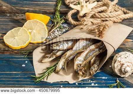 Sun-dried Smelt In A Paper Package. Salted Fish With Marine Decor. Lemon, Fresh Rosemary, Sea Rope