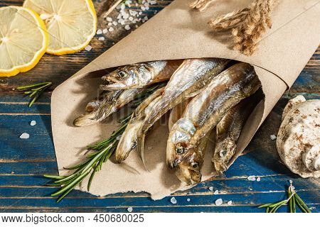 Sun-dried Smelt In A Paper Package. Salted Fish With Marine Decor. Lemon, Fresh Rosemary, Sea Rope
