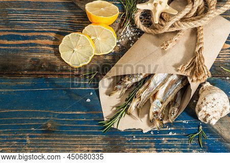 Sun-dried Smelt In A Paper Package. Salted Fish With Marine Decor. Lemon, Fresh Rosemary, Sea Rope