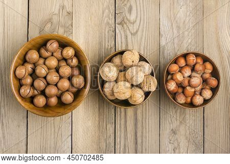 Natural Organic Macadamia, Walnut, Hazelnut Nuts In Wooden Bowl On Wooden Background Flat Lay Top Vi