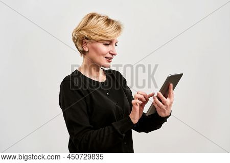 Concentrated Adult Caucasian Woman Using And Watcing On Digital Tablet. Pretty Blonde Person. Concep