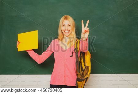 Female Teacher In The Classroom On The Chalkboard. College Girl In Class. Student Girl Holding Empty