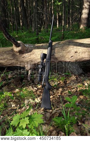 Black Hunting Rifle With Scope Optics Leaning Against A Fallen Tree