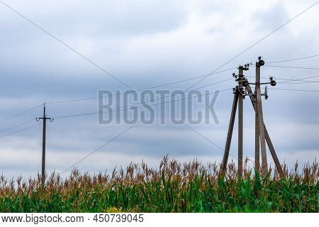 Power Line In A Corn Field Against The Background Of A Cloudy Sky