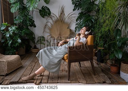 Calm Young Woman Gardener In Wireless Headset Listen Music Relax At Home Garden Dream. Peaceful Mill