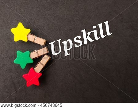 Top View Colored Wooden Clips With Text Upskill On Black Background.