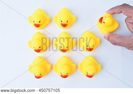 Hand Grabs Toy Duck From The Group Of Workers. Firing Someone Concept.
