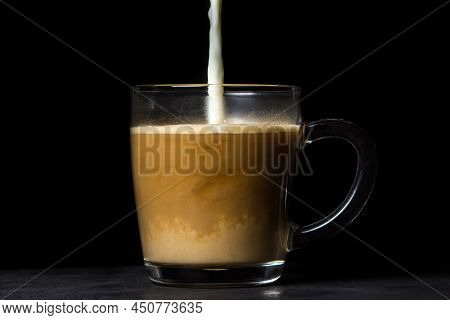Cream Is Poured Into Coffee On A Black Background. Tonic Coffee Drink. Coffee With Milk