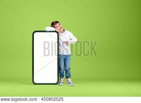 A Boy Kid Smiling, Full Length, Finger Point At Mobile Phone Mock Up Copy Space Screen, Blue Backgro