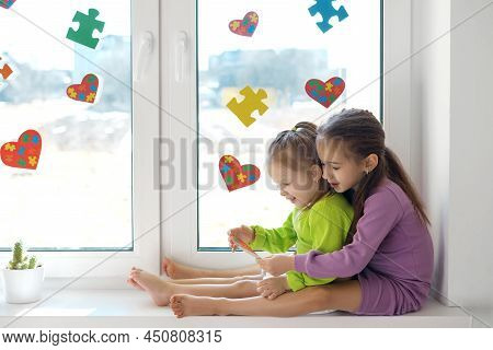 Girl Gave Her Little Sister A Heart-shaped Card With Puzzles For Autism Day. The Windows Are Decorat