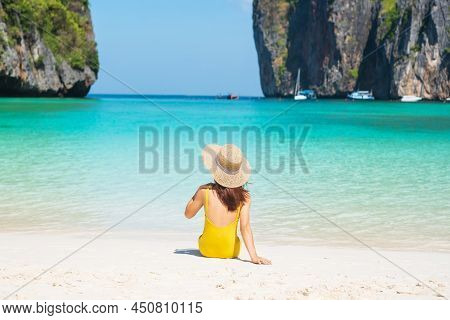 Woman Tourist In Yellow Swimsuit And Hat, Happy Traveller Sunbathing At Maya Bay Beach On Phi Phi Is