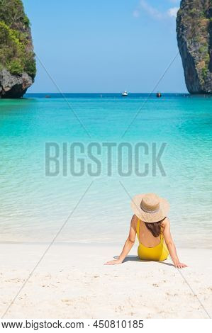 Woman Tourist In Yellow Swimsuit And Hat, Happy Traveller Sunbathing At Maya Bay Beach On Phi Phi Is