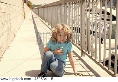 Paused For Breath. Boy Relax Hunkering Down On Promenade. Boy Child Take Short Rest