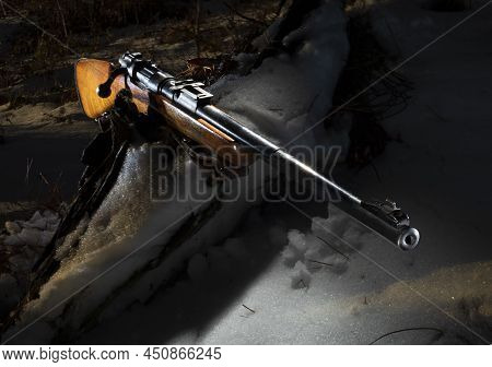 Surplus Military Bolt Action Rifle Sporterized For Hunting On A Snowy Log Outside