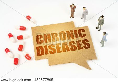 Medical Concept. On A White Surface Are Pills, A Pen, Miniature Figurines Of People, A Sign With The