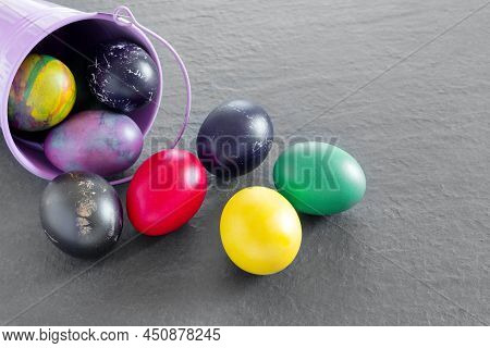 Lots Of Bird Bucket  With Painted Easter Eggs On A Dark Tabletop. Holiday Greeting Card. Concept Cre