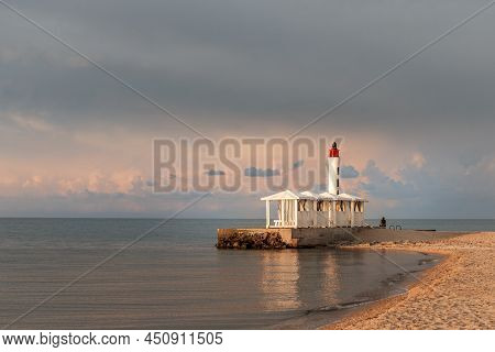 Lighthouse And Gazebos In The Sea During Sunset. Calm On The Sea. Seaboard, Seascape