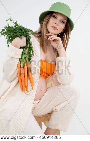 Vertical Beauteous Pregnant Woman Green Hat, Orange Top And Flax Clothes, Naked Belly Looking Camera