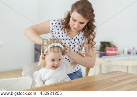 Mother Helps To Put On Cochlear Implant For Her Deaf Little Daughter. Hearing Aid And Deafness Conce