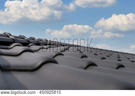 Ridge Tile On The Roof Of A Single-family House Covered With A New Ceramic Tile In Anthracite Agains