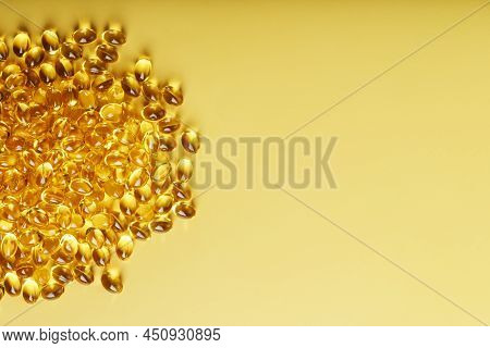 Heap Of Transparent Fish Oil Capsules On Yellow Background With Free Space