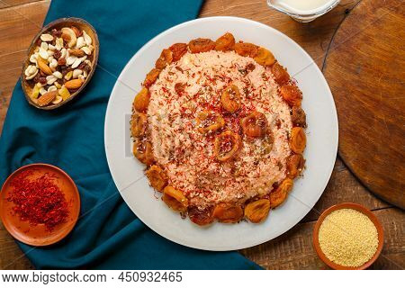 Couscous Masfouf With Dried Fruits And Nuts On A Wooden Table Next To Saffron, And Couscous Grits In