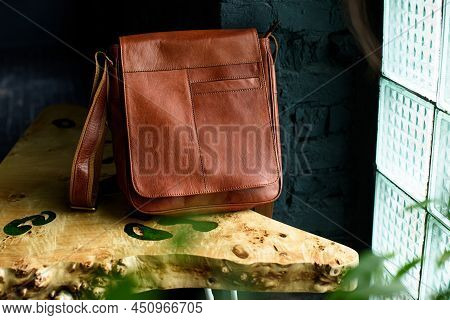 Close-up Photo Of Orange Leather Messanger Bag On A Wooden Table