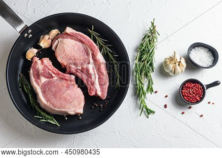 Fresh Pork Steak In A Frying Grill Pann On A White Stone Background With Rosemary Garlic Peppercorns