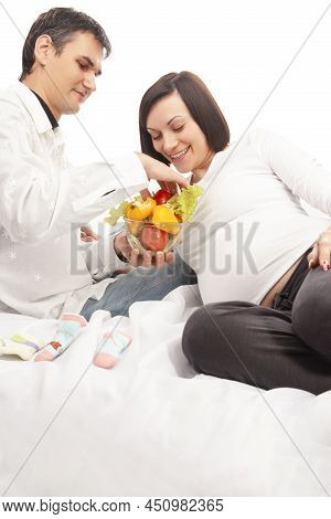 Pregnancy Concepts. Portrait Of Husband Man Offering His Pregnant Wife Fresh Vegetables On Glass Bow