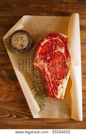 raw beef Rib bone  steak  on paper  and table with 2lb iron weight