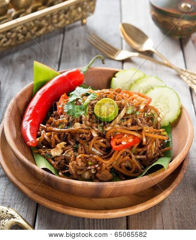 Asian spicy fried noodles, ready to serve on dining table.