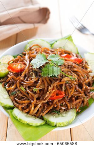 Asian style spicy fried noodles, ready to serve on dining table.