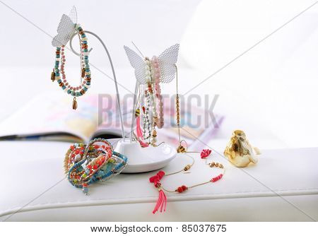Decorative stand with jewelry and bijouterie on sofa in room