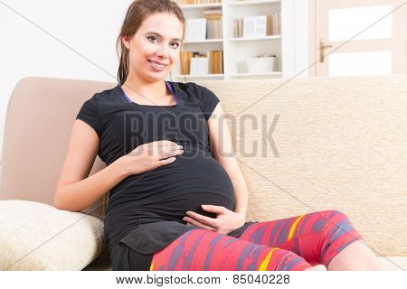 Young pregnant woman resting after doing finess at home
