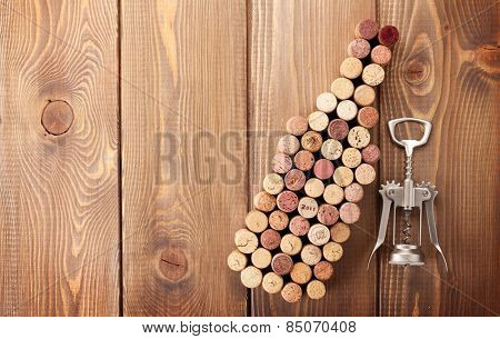 Wine bottle shaped corks and corkscrew over rustic wooden table background. Top view with copy space