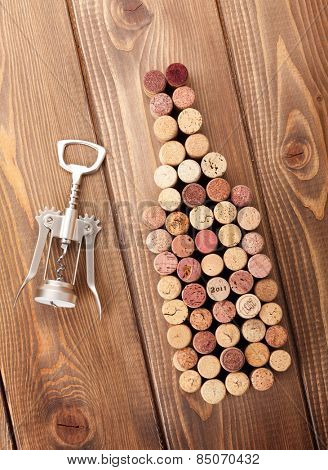 Wine bottle shaped corks and corkscrew over rustic wooden table background. Top view