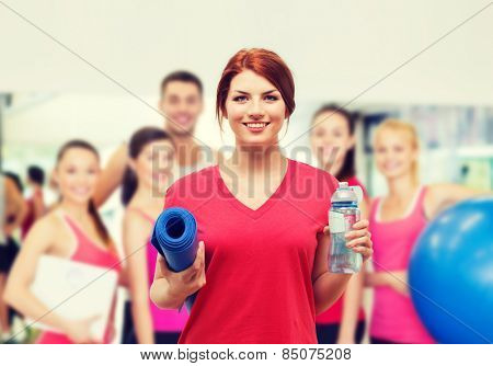 fitness, home and diet concept - smiling teenage girl with bottle of water and yoga mat after exercising at home