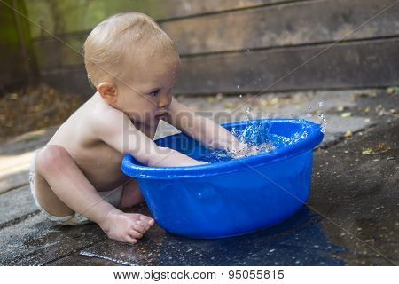 ребенок играет с водой в тазике