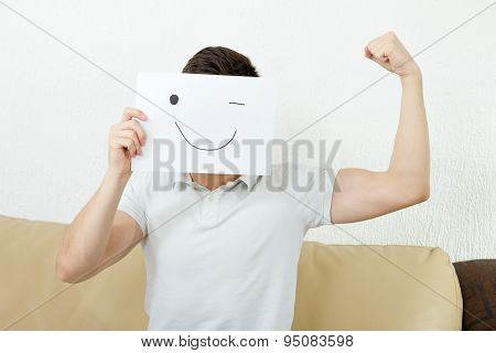 Boy Winks And Raises Fist. Young Male Advertises Successful Model Body. Man Cover His Face With Happ