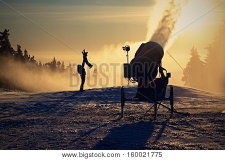 Father is playing with his children next to the snow cannon.