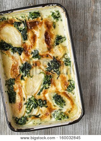 close up of rustic golden spinach potato gratin dauphinois