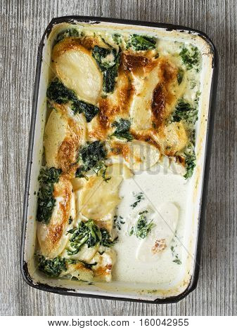 close up of rustic golden spinach potato gratin dauphinois