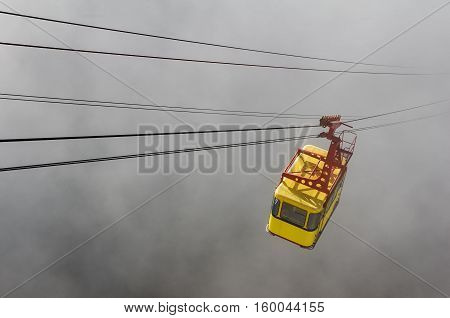 yellow cable car rides through the fog