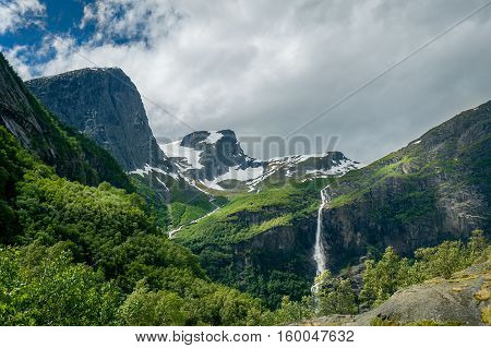 Beautiful green mountain slopes and waterfalls on the hiking path to Briksdalsbreen glacier viewpoint. Briksdal, Norway.