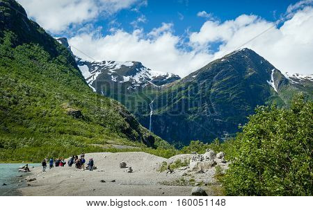 Group of tourists at the lake shore, popular hiking path finish and Briksdalsbreen glacier viewing point. Briksdal, Norway.