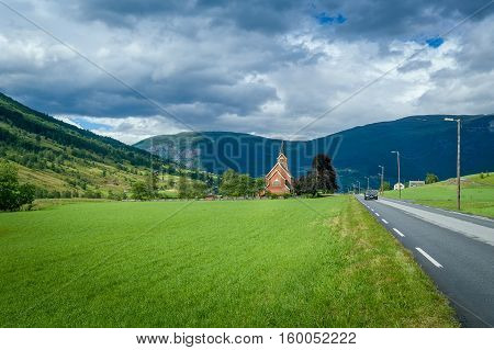 Small church and road in norwegian fields. Rural country landscapes of Norway.