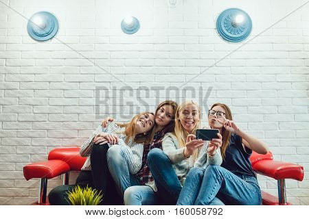 Beautiful girls sitting on the couch, have fun and make selfie Hostel