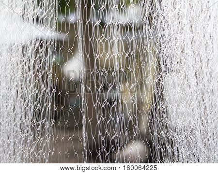 Abstract white textile blurry background. Water like abstraction in blur. Polyester net closeup photo for backdrop. Thin thread blurry background. Fisherman net close-up image. Plastic curtain picture
