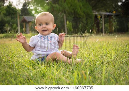 happy young baby child sittng on grass on beautiful summer day in park